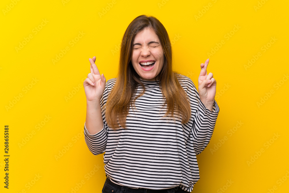 Young girl over yellow wall with fingers crossing Young girl over yellow wall with fingers crossing
