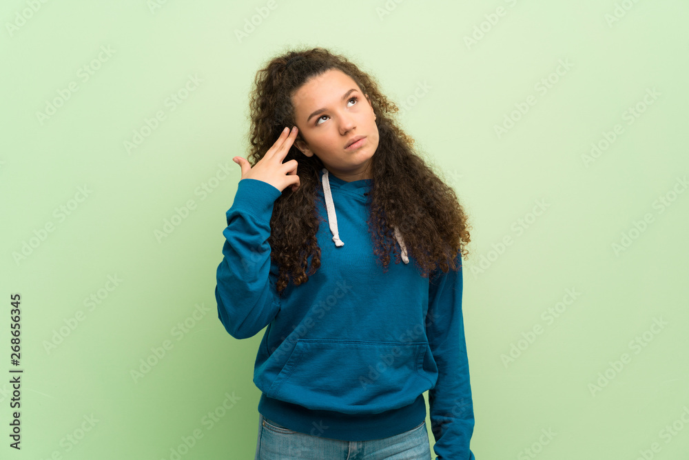 Teenager girl over green wall with problems making suicide gesture Teenager girl over green wall with problems making suicide gesture