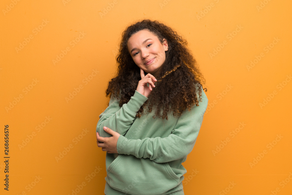 Teenager girl over ocher wall thinking an idea while looking up Teenager girl over ocher wall thinking an idea while looking up
