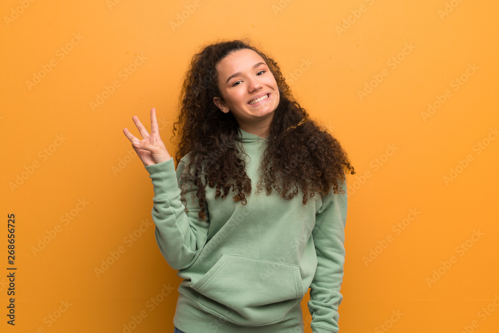Teenager girl over ocher wall happy and counting three with fingers Teenager girl over ocher wall happy and counting three with fingers