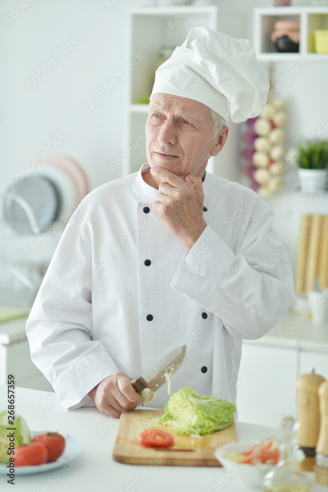 Portrait of elderly male chef cooking at kitchen Portrait of elderly male chef cooking at kitchen