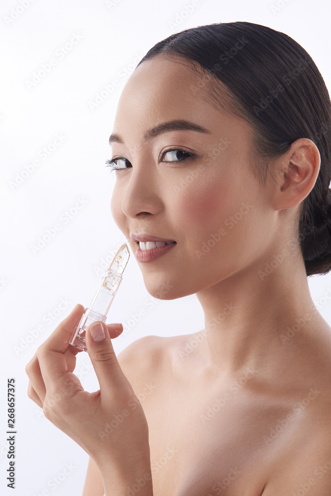 Glad young lady putting on lipstick and smiling Glad young lady putting on lipstick and smiling