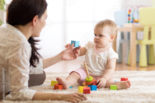 Mom or nanny playing with little child, indoors