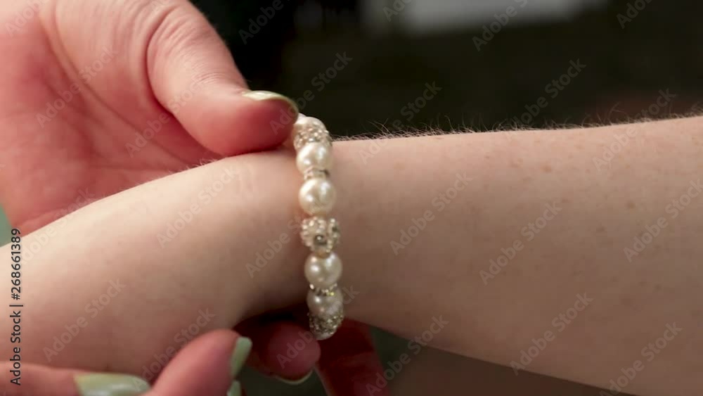 Close-up of rolling bracelet up a woman's arm.