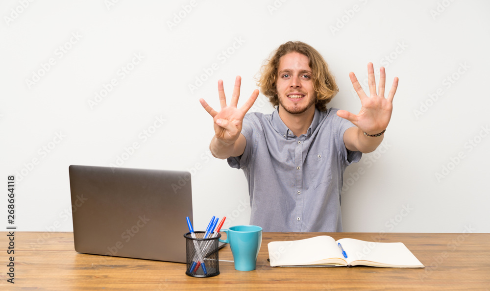 Blonde man with a laptop counting nine with fingers Blonde man with a laptop counting nine with fingers