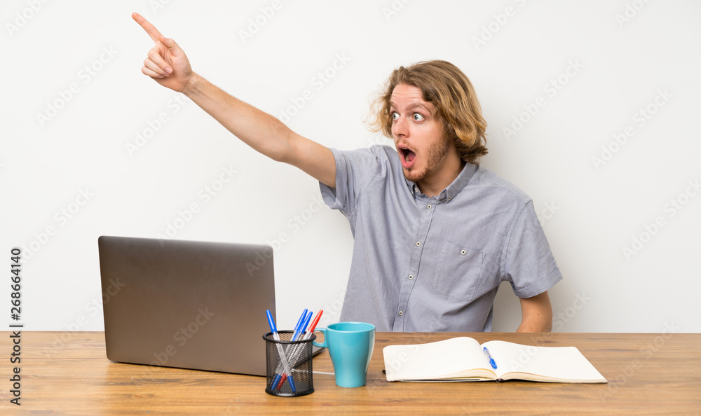 Blonde man with a laptop pointing away Blonde man with a laptop pointing away