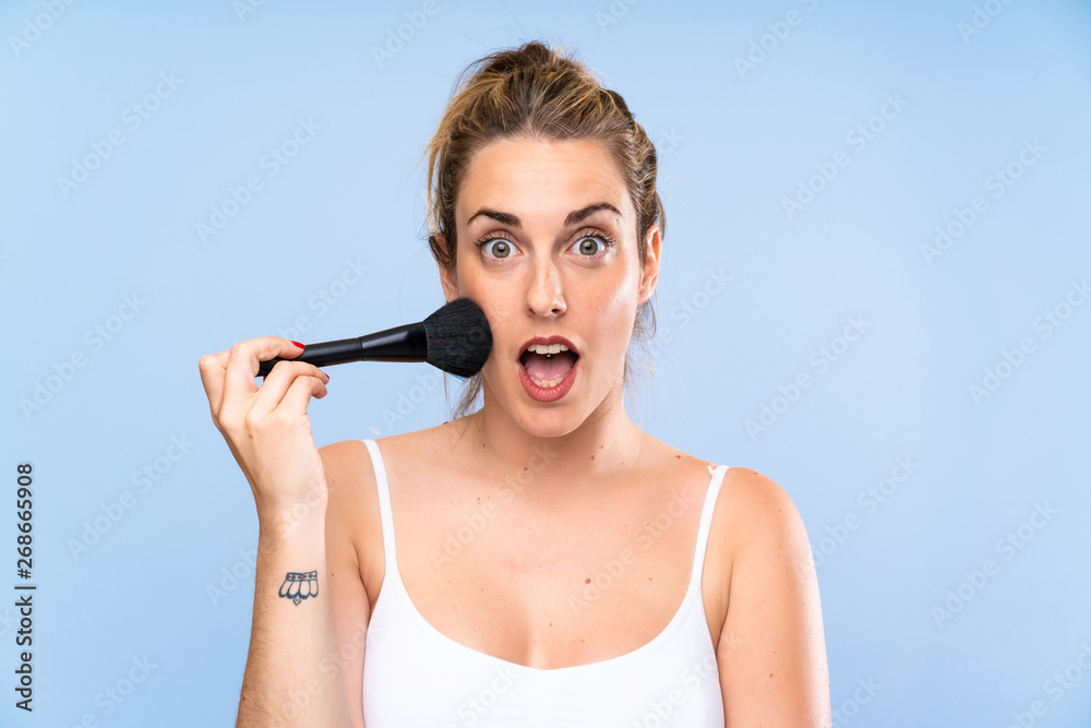 Young blonde woman with makeup brush doing surprise gesture Young blonde woman with makeup brush doing surprise gesture