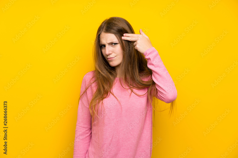Young woman with long hair over isolated yellow wall with problems making suicide gesture Young woman with long hair over isolated yellow wall with problems making suicide gesture