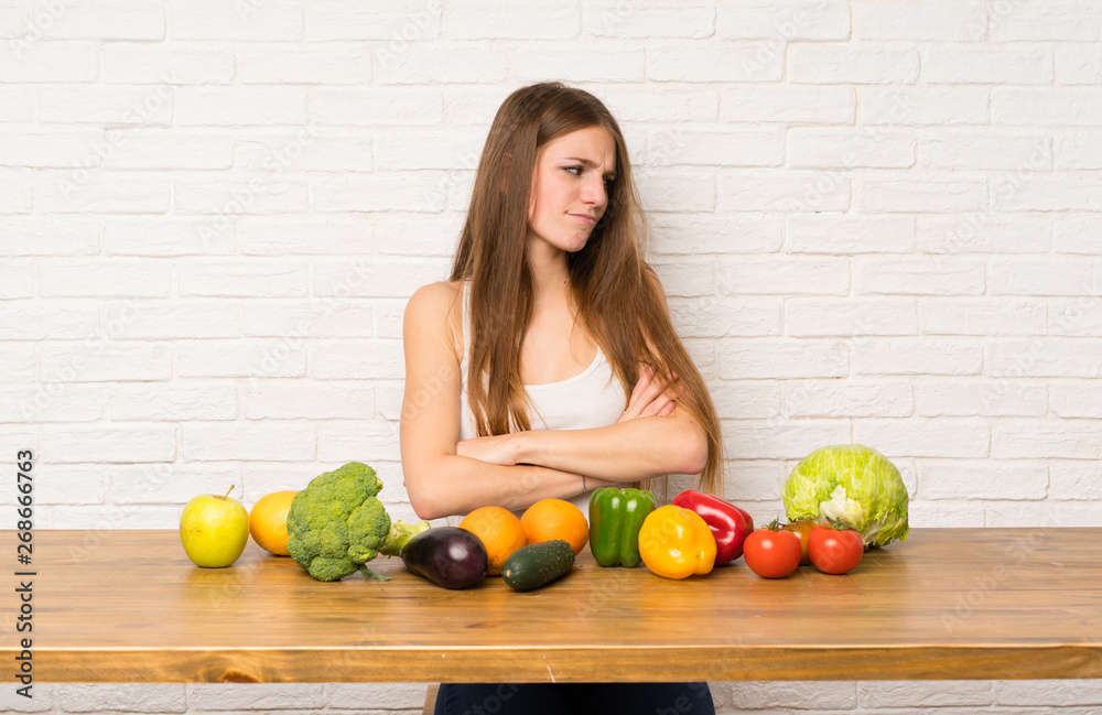 Fototapeta premium Young woman with many vegetables standing and thinking an idea