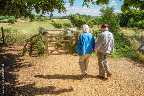 Fényképezés Elderly couple hold hands,walking in the British countryside.