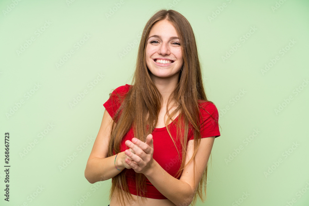 Young woman with long hair over isolated green wall applauding Young woman with long hair over isolated green wall applauding