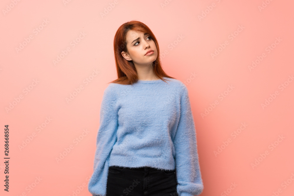 Obraz premium Young redhead woman over pink background looking up with serious face