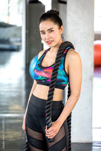 portrait of  Beautiful athletic Asian woman posing with battle ropes at sport fitness gym . workout . exercise