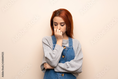 Young redhead woman over isolated background having doubts
