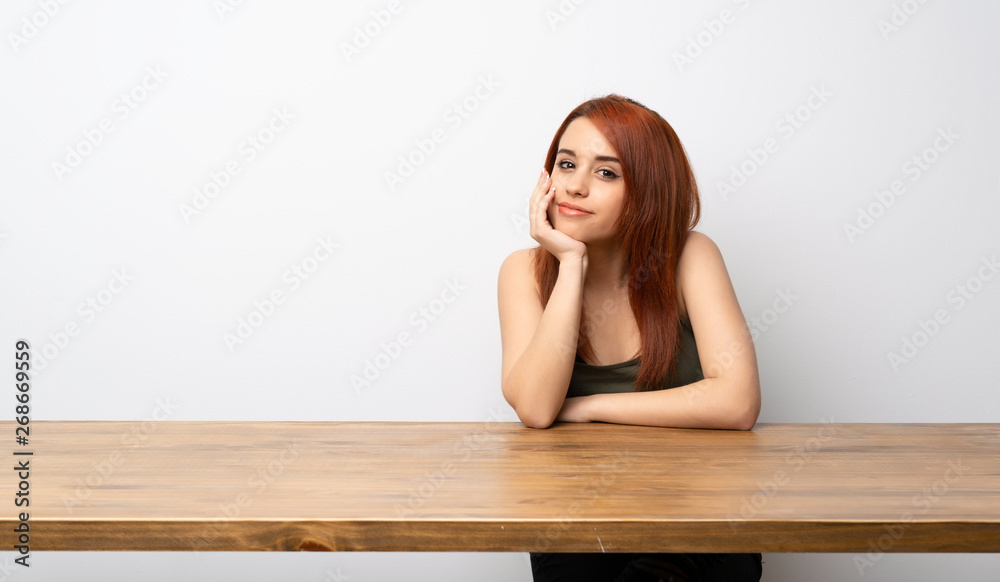 Young redhead woman at desk laughing looking to the front Young redhead woman at desk laughing looking to the front