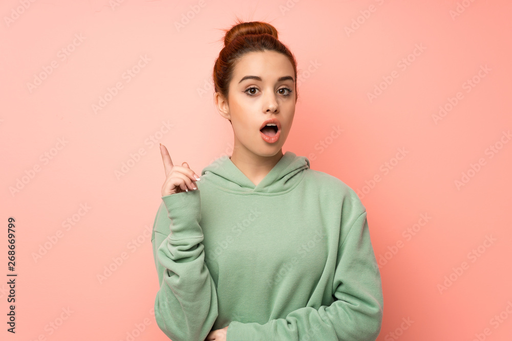 Young redhead woman with sweatshirt thinking an idea pointing the finger up Young redhead woman with sweatshirt thinking an idea pointing the finger up