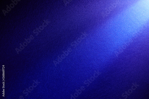 Dark blue beam of light shining from top to bottom on a dark background.