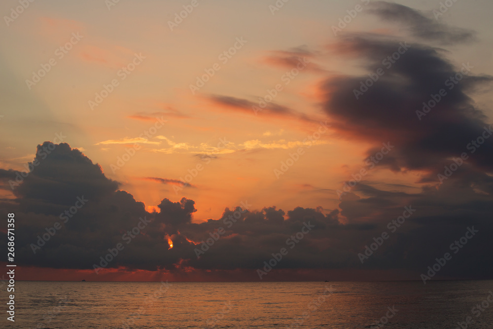 Powerful clouds hang over the sea and burn red Powerful clouds hang over the sea and burn red