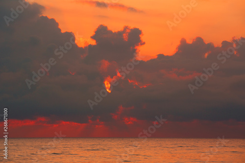 Powerful clouds hang over the sea and burn red photo