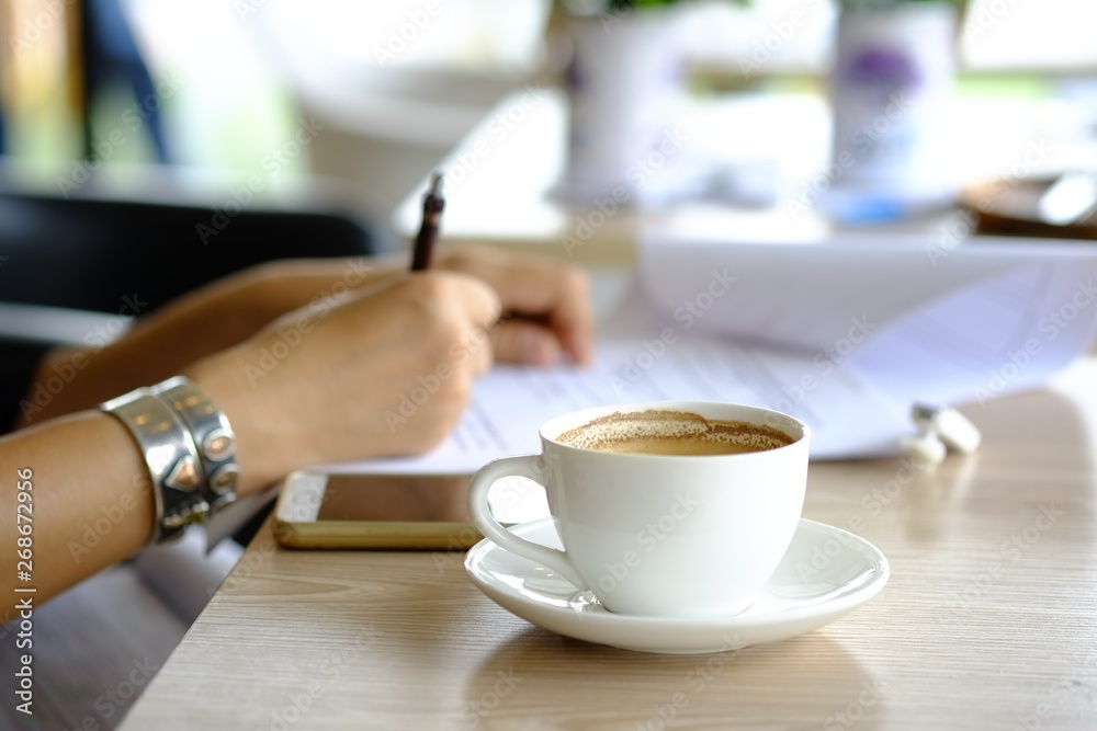 Fototapeta Hot coffee in white ceramic mug for drinking during relaxed work hours.