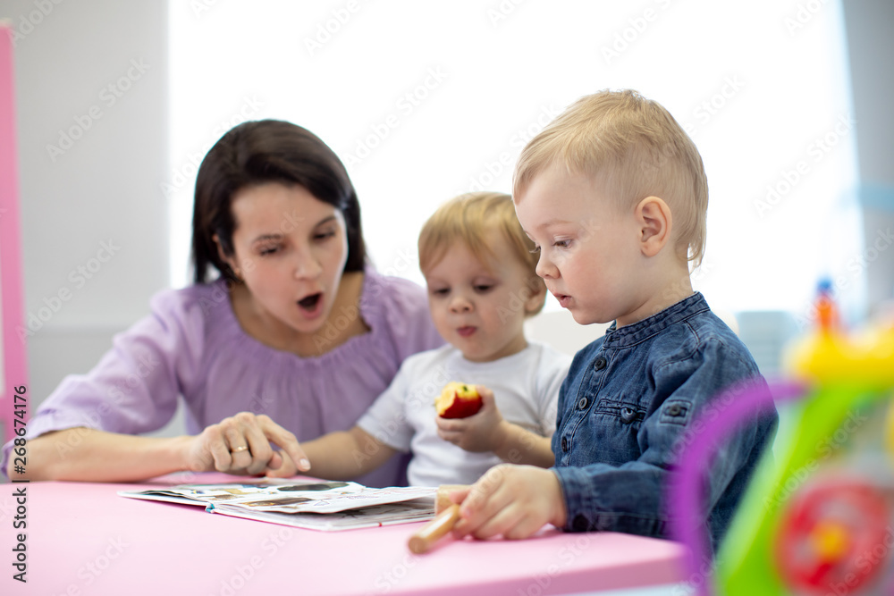 Babysitter reads book to kids in nursery