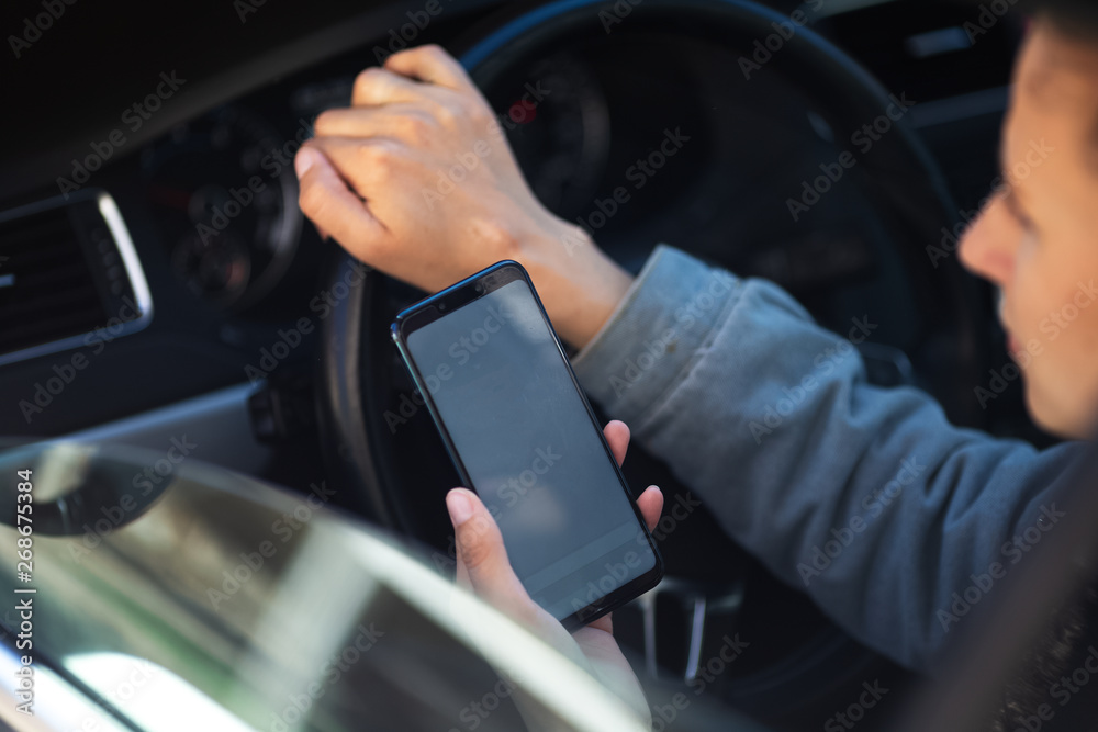 Young girl driving the car with smartphone in hand