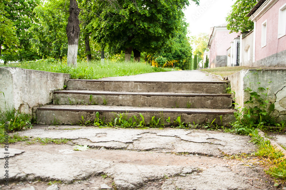 old wide concrete steps. Against the backdrop of green trees. Summer day