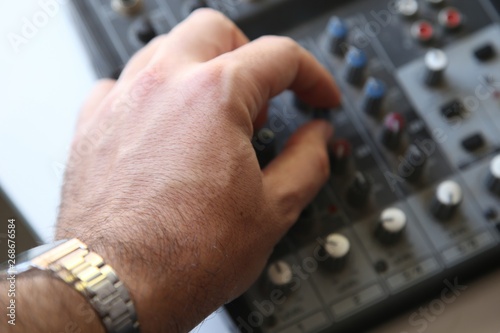 A sound engineer turning an equalization knob on an old mixing console. Music production concept image. This image has selective focusing. 