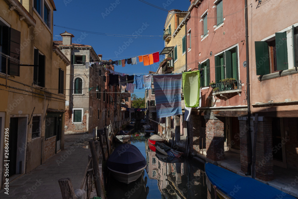 Narrow Canal View with boats and clothes on the line and the typical Venetian Buildings. Venice, Italy