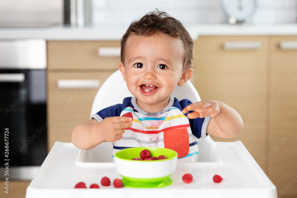 Happy baby in high chair eating strawberries Happy baby in high chair eating strawberries