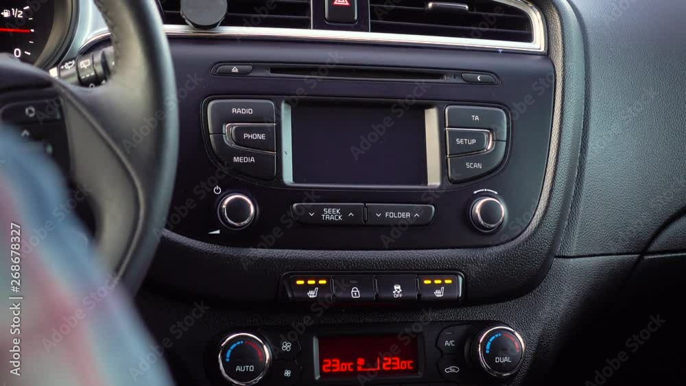 Hand presses a Heated Seat High button on a dashboard in a car Hand presses a Heated Seat High button on a dashboard in a car