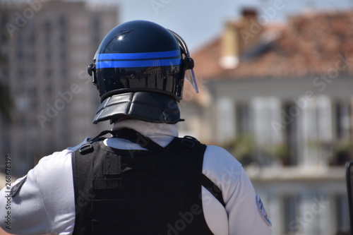 Helmeted police officer photographed from behind during a protest © Gérard Bottino