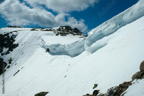 Cornices of snow on top of a snowy and sunny mountain. photo