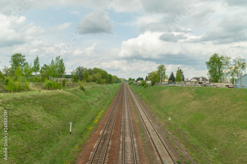 railway goes through the green field, the sky with clouds