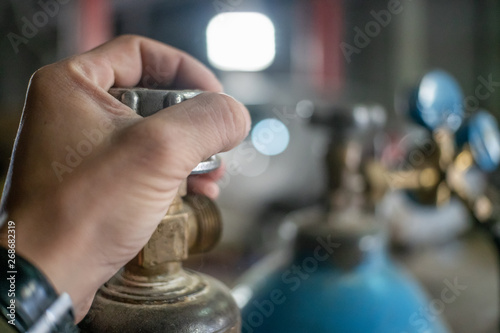 Closeup man's hand operating valve of gas cylinder for welding
