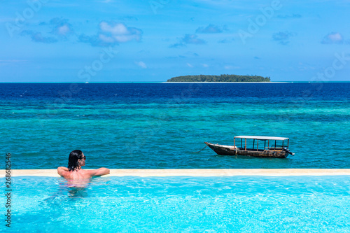 one caucasian woman enjoying vacations  sunbathing on a infinity swimming pool by the seaside looking at the idian ocean Muyuni  in Unguja aka Zanzibar Island Tanzania East Africa photo