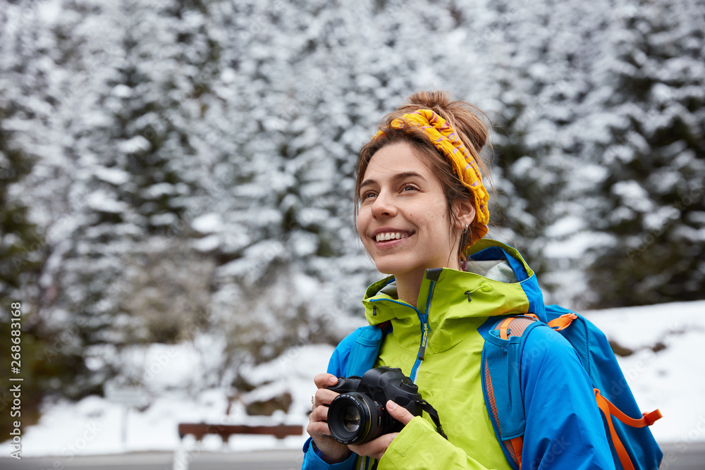 Φωτογραφία Happy female hiker with broad smile, wears casual clothes, holds photocamera, ma