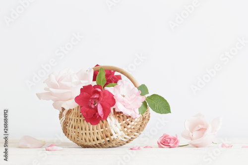 beautiful roses in basket on wooden table