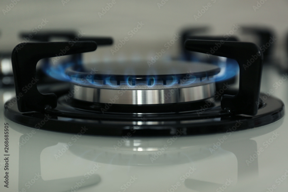 Gas burner with blue flame on modern stove, closeup Gas burner with blue flame on modern stove, closeup