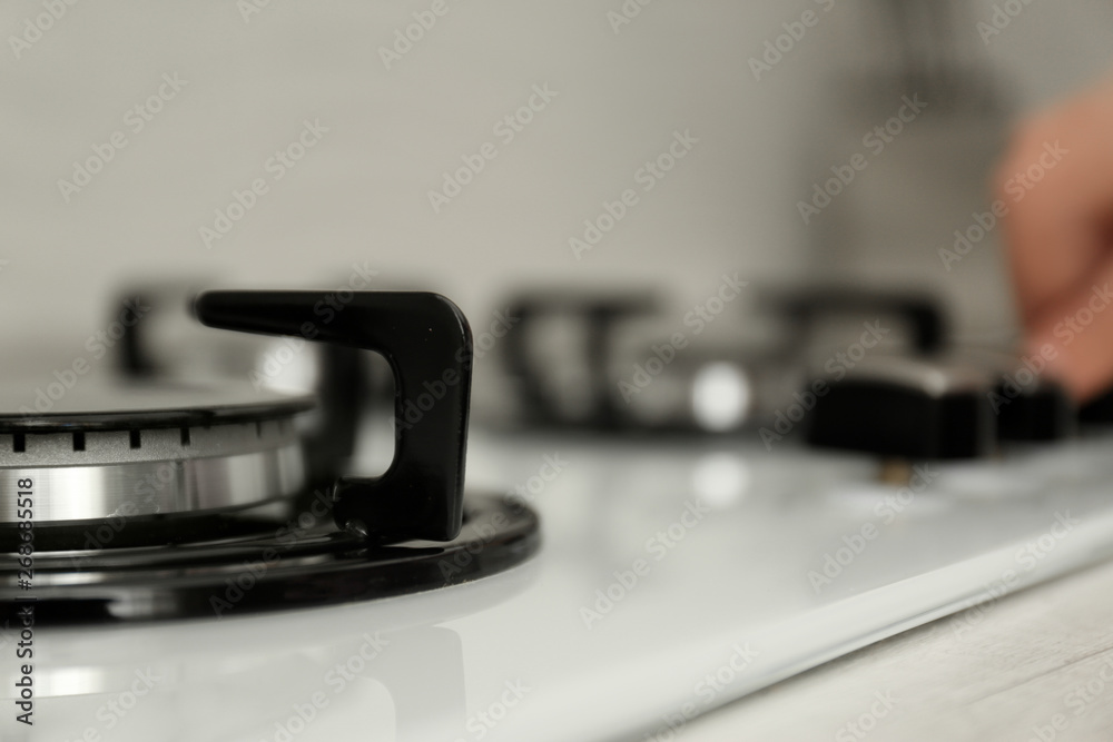 Woman regulating cooking mode on gas stove panel, closeup Woman regulating cooking mode on gas stove panel, closeup