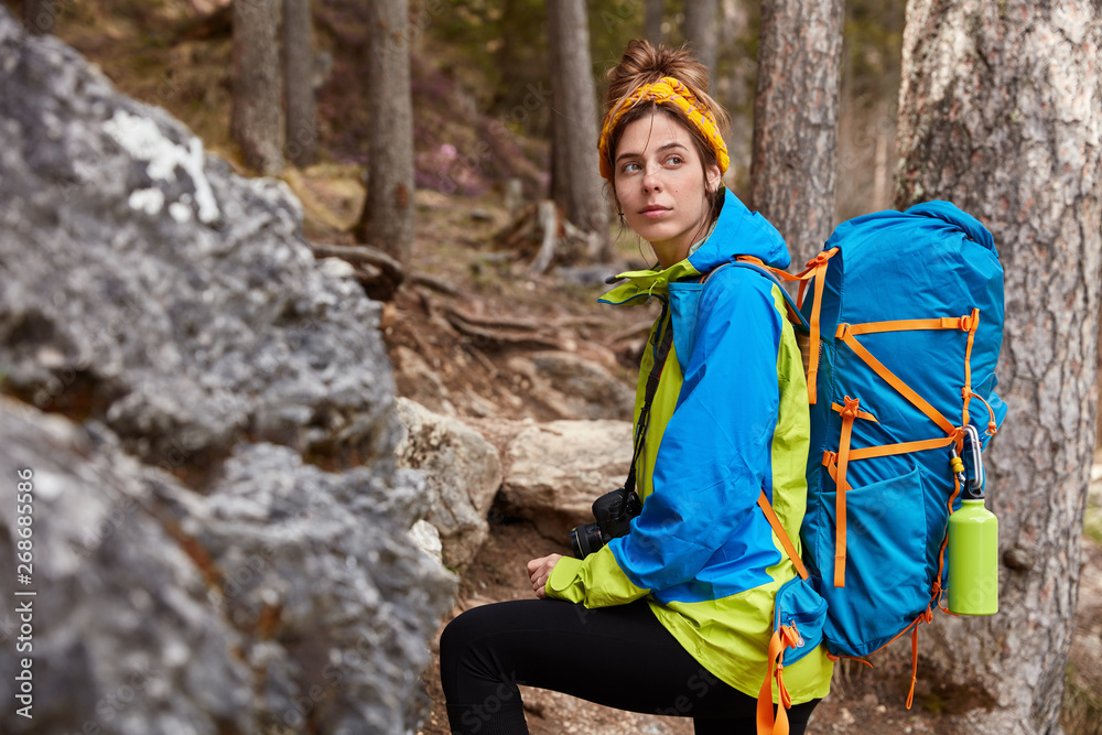 Φωτογραφία Photo of pensive tourist in bright anorak, carries rucksack, photocamera on neck