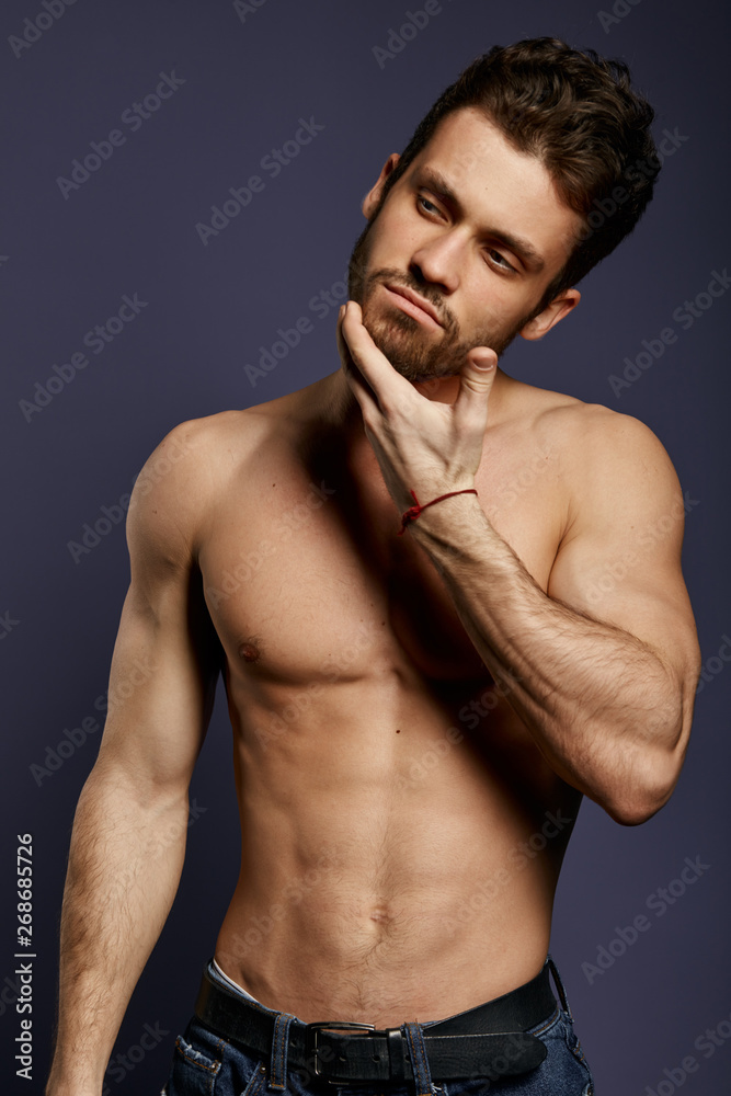 Obraz premium Muscular sexy man holding chin with finger, as he is dreaming about a new shaver ,isolated on black background. studio shot.
