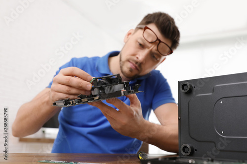 Male technician repairing computer at table indoors