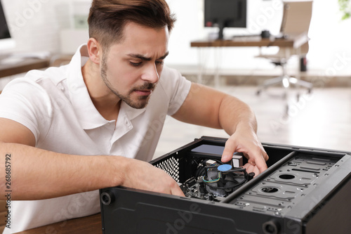 Male technician repairing computer at table indoors