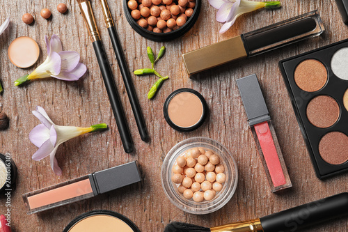 Many different makeup products and spring flowers on color background, flat lay