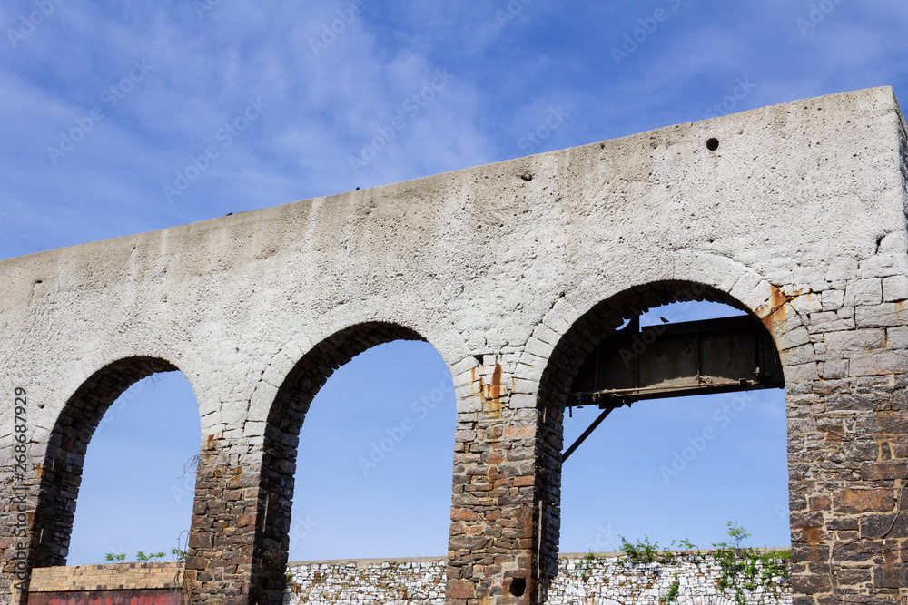 Old wall with three open archways that once held windows, abandoned building ruins, horizontal aspect