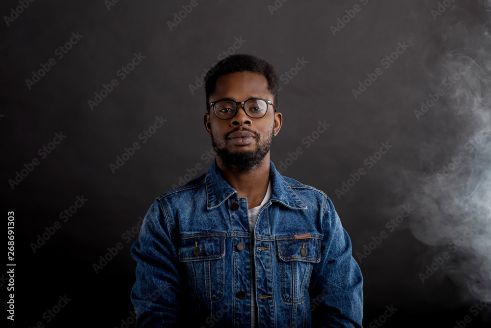 Portrait of african guy in denim jacket in dark