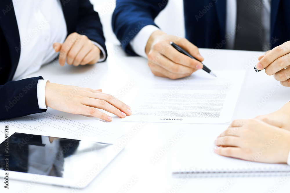 Group of business people and lawyers discussing contract papers sitting at the table, close-up. Successful teamwork, cooperation and agreement concepts