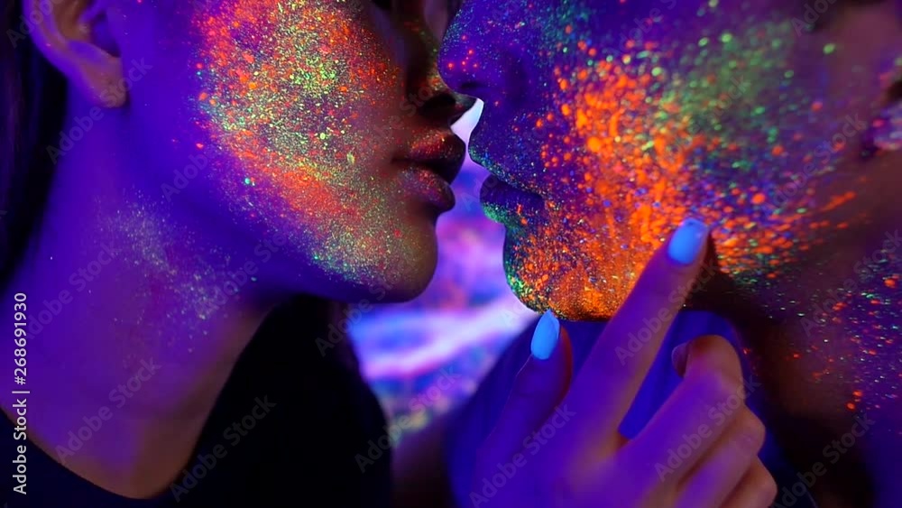 Couple kissing in the disco club with fluorescent paintings on the faces