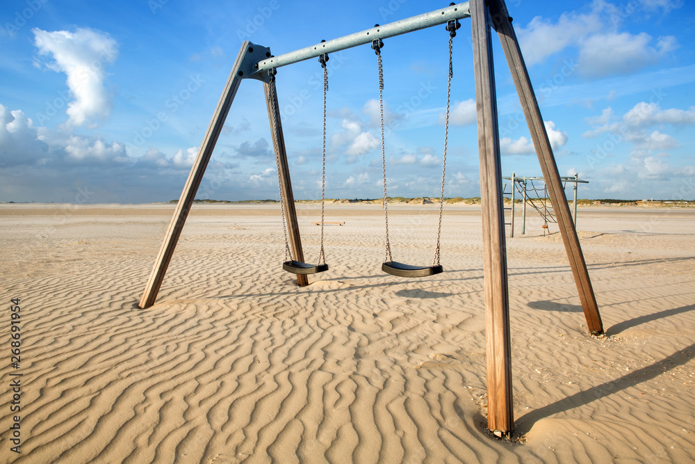 two swings in the sand by the beach two swings in the sand by the beach